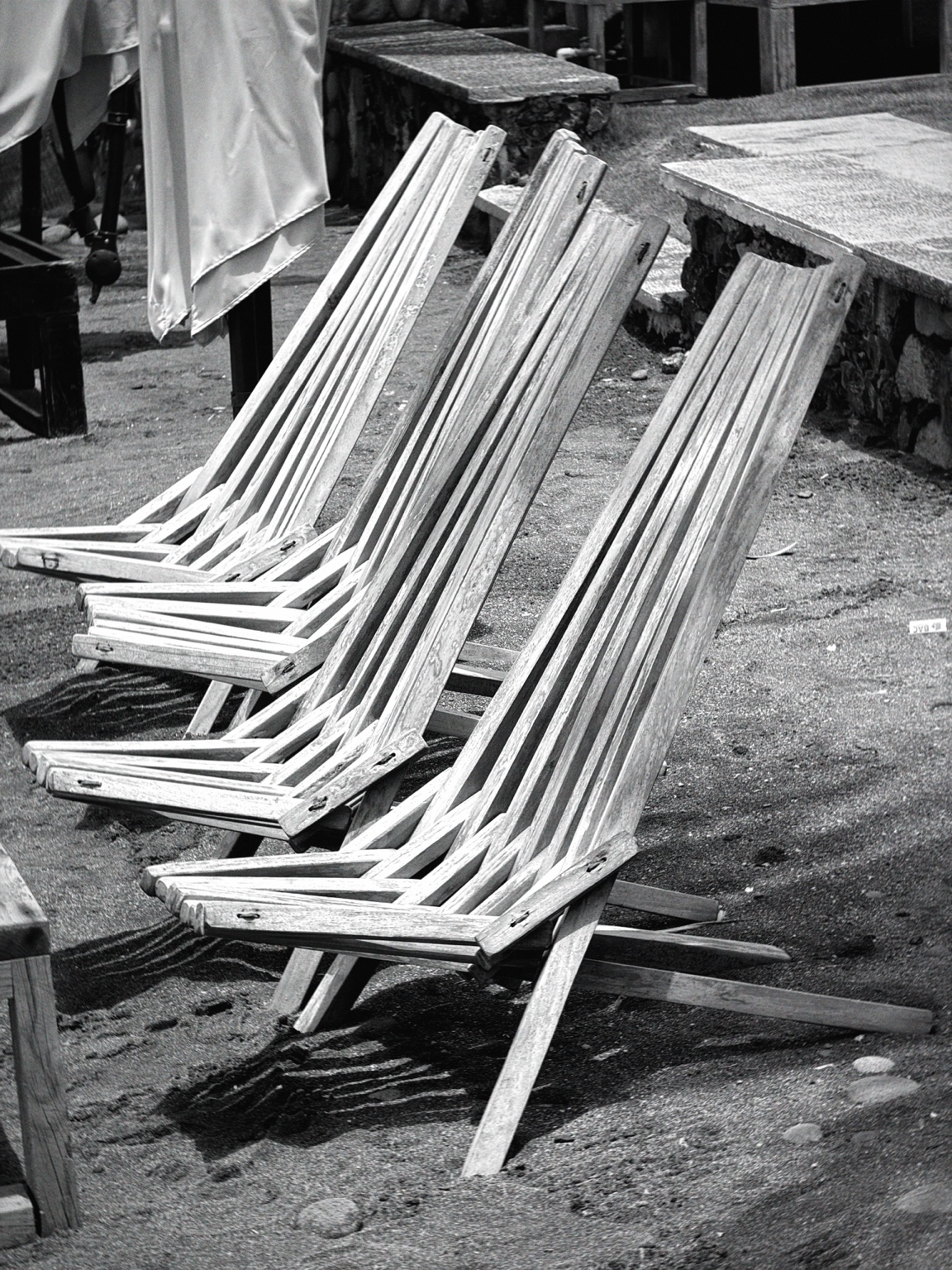 Tres sillas de madera alineadas sobre la arena